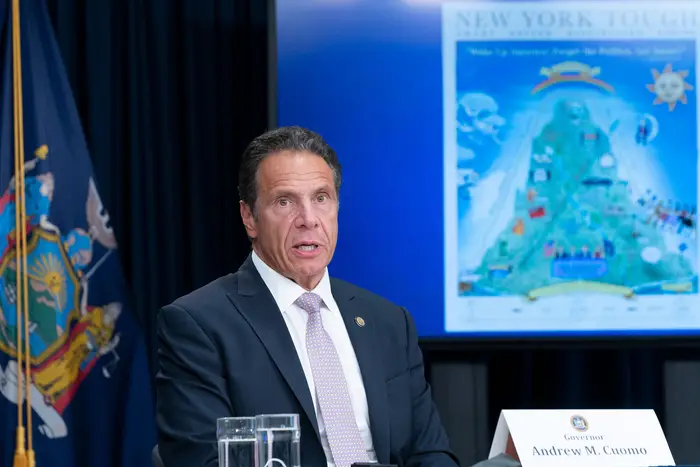Governor Andrew Cuomo speaks during a presser conference with an image of his New York Tough poster behind him